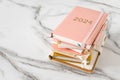 Pink coral colored diary for the year 2024 and many other diaries, pen, marble background Royalty Free Stock Photo