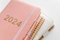 Pink coral colored diary for the year 2024 and many other diaries, pen, white background Royalty Free Stock Photo