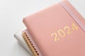 Pink coral colored diary for the year 2024 and many other diaries, pen, white background Royalty Free Stock Photo