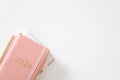 Pink coral colored diary for the year 2024 and many other diaries, pen, white background Royalty Free Stock Photo
