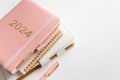 Pink coral colored diary for the year 2024 and many other diaries, pen, white background Royalty Free Stock Photo