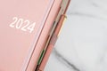 Pink coral colored diary for the year 2024, pen, marble background Royalty Free Stock Photo