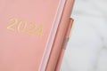 Pink coral colored diary for the year 2024, pen, marble background Royalty Free Stock Photo