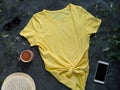 Yellow plain t-shirt mockup coffee cup dark background. Blank cotton shirt template creative design. Female illuminating summer Royalty Free Stock Photo