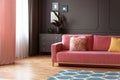 Pink couch with pillows in spacious grey living room interior wi