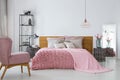 Pink cozy blanket and duvet on king size bed in contemporary bedroom interior, copy space on empty white wall Royalty Free Stock Photo