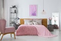 Pink woolen blanket and duvet on warm king size bed in classy bedroom interior, abstract painting on empty wall Royalty Free Stock Photo