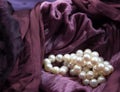 Pink cultured pearls on burgundy velvet crumpled dress background