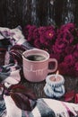 A pink cup of coffee, burgundy asters, autumn grape leaves and a scarf. A gray candle is burning.