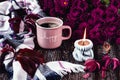 A pink cup of coffee, burgundy asters, autumn grape leaves and a scarf. A gray candle is burning.