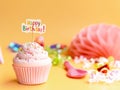 Pink cupcake with Happy Birthday text on beige background