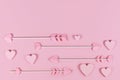 Pink cupid`s arrows with heart shaped tips and wooden hart ornaments Royalty Free Stock Photo