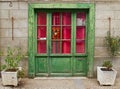 Pink curtains behind a weathered green glass paneled door