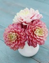 Pink dahlias in white jug on old wooden background