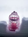 Pink decorative lantern with a burning candle in the snow against the backdrop of a winter landscape, bad weather
