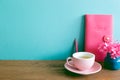 Pink diary, pencil, cup of tea, dry flowers on wooden table. mint blue wall Royalty Free Stock Photo