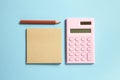 Digital calculator and memo note pad and brown colored pencil on blue background Royalty Free Stock Photo