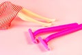 Pink disposable woman razors with doll legs on light pastel background. Hair removing, epilation procedure and shaving concept. Royalty Free Stock Photo