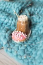 Pink donut with marshmallow and hot chocolate in glass cup on blue merino knit blanket. Lights on background Royalty Free Stock Photo