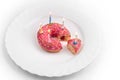 Pink donut on white plate like birthday cake with candles on white background Royalty Free Stock Photo