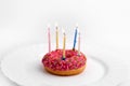 Pink donut on white plate like birthday cake with candles on white background Royalty Free Stock Photo