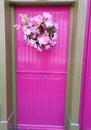 Pink door with floral wreath and fairy door Royalty Free Stock Photo