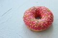 Pink doughnut with sprinkles on white textured background
