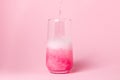 A pink drink is poured into a glass on a pink background. Carbonated sweet water. Royalty Free Stock Photo