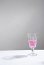 pink drink in wine glass with minimalist gray background