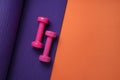 Pink dumbbell and purple yoga mat on orange table, fitness healthy and sport concept Royalty Free Stock Photo