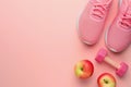 Pink dumbbell, running snickers and apples on pastel pink background with copy space for text. Training with weights, fitness,