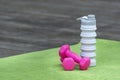 Pink dumbbells and silicone water bottle on yoga mat. Close up. Equipment for sports