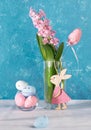 Pink Easter decorations decorative eggs, cute wooden bunny, jacinth flower in glass. Vertical format