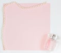 Pink empty card, sheet for writing. Layout for adding tags with a pearl necklace and perfume. Top view, flat lay, copy space