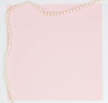 Pink empty card, sheet for writing. Layout for adding tags with a pearl necklace. Top view, flat lay, copy space