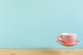 Pink empty coffee cup floating on wooden table