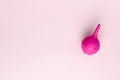 Pink enema, squirt or soft tip syringe for medical purposes on pastel pink.