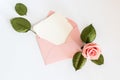 Pink envelop with white card and rose. Flat lay.