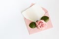 Pink envelop with white card and rose. Flat lay.