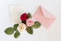 Pink envelop with white card and roses. Flat lay.