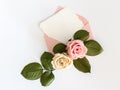 Pink envelop with white card and roses. Flat lay.