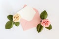 Pink envelop with white card and roses. Flat lay.