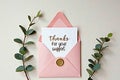 Pink envelope with thanks card and wax seal on beige background with greenery Royalty Free Stock Photo