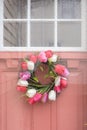 Pink exterior door with Spring wreath on rainy day