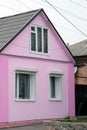 Pink facade of a one-story house with a triangular roof.