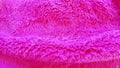 Pink faux fur folded in a wave. Soft texture of the pile, overflow of light on the villi. Material for sewing garments. Warm Wool