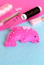 Pink felt dolphin toy on a blue background. Funny sewing and craft activity for children