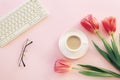 Pink female workplace with keyboard, tulip flowers, coffee cup and glasses. Spring holidays, mothers day concept. Top Royalty Free Stock Photo