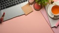 Pink feminine creative workspace with laptop, cosmetics, tea cup, stationery and copy space