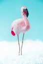 Pink flamingo on turquoise background with snow, selective focus top view